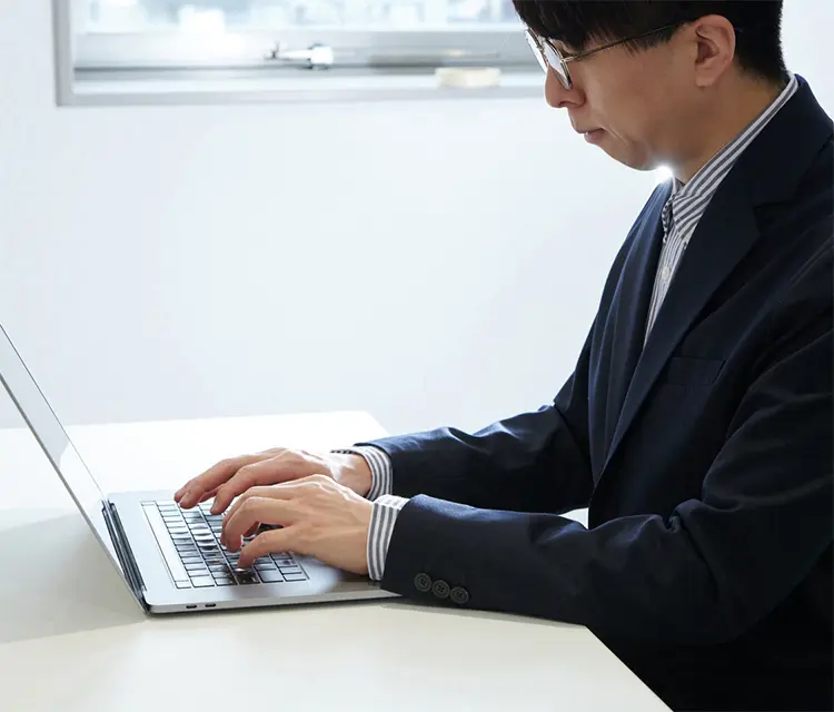 写真：ノートPCにタブレットを繋いでイラストを描いてる女性社員